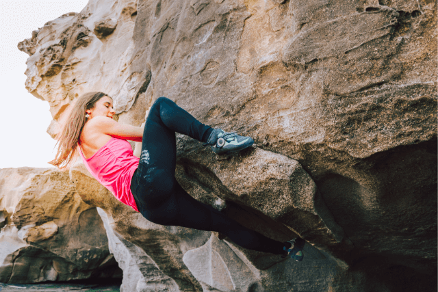 Young rock climber woman climbing a rock wall