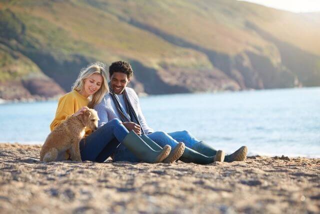 Couple sat on beach in North Wales with dog.