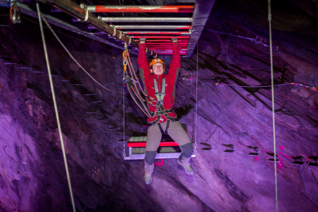 Girl hanging from a rope in Zip World Cavern