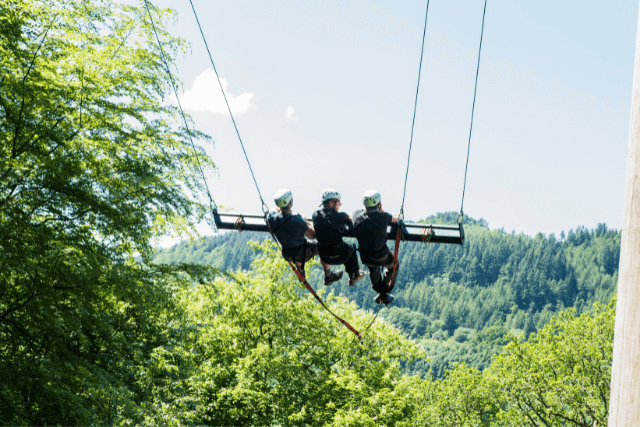 Three adults swinging on a giant swing at Zip World Sky Ride