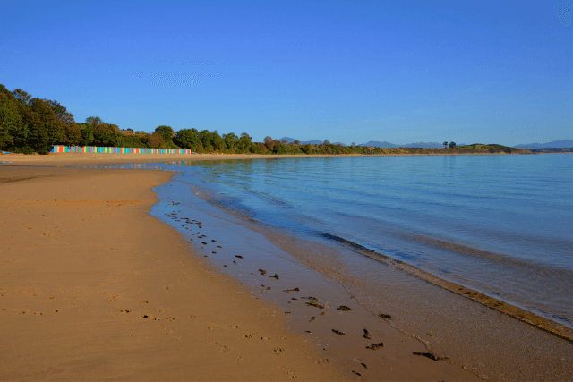 Llanbedrog Beach with colourful beach huts in the distance