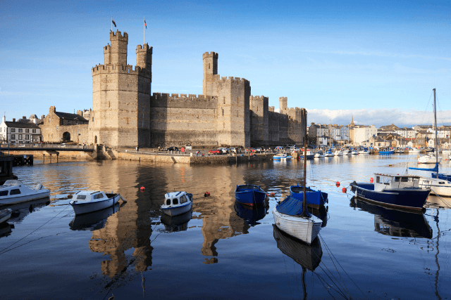 Caernarfon castle with boats in the harbour.