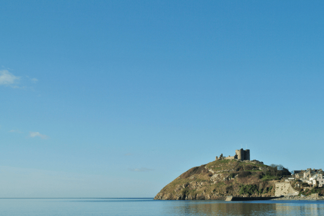 Criccieth Castle on a hill, surrounded by the sea.