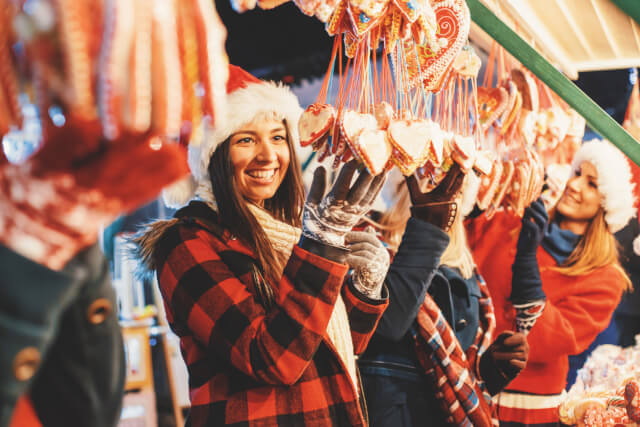 Woman browsing hanging heart decorations at a christmas market. 