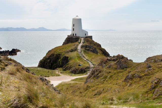 Llanddwyn Island in Anglesey, surrounded by green hills with mountains in the background.